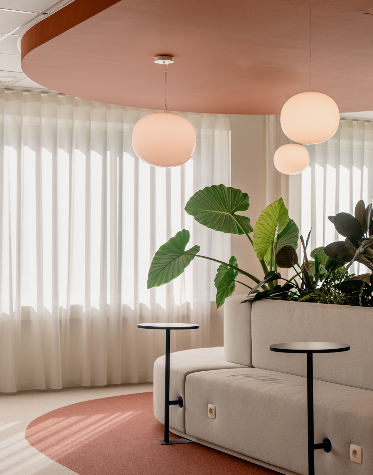 astara-portfolio-2 voorbeeld van een interieur ontworpen door Three of a kind met een peach plafond, planten in het midden, afgeronde meubels en zitbanken in het wit en ronde, witte hanglampen